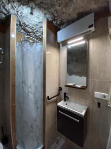 un baño con ducha y lavabo en Casa Cueva EL PORTÓN, en Alcalá del Júcar