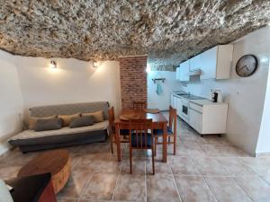 Una cocina y una sala de estar con una mesa y un sofá. en Casa Cueva EL PORTÓN, en Alcalá del Júcar
