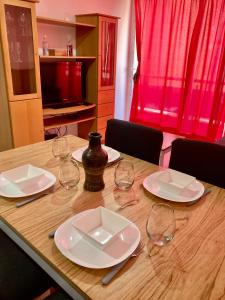 a wooden table with plates and wine glasses on it at 6-Maravilloso departamento morón centro in Morón
