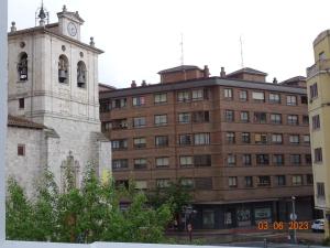 a building with a clock tower next to a building at Apartamentos Cuéntame Burgos - VUT in Burgos