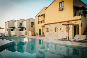 a swimming pool with two chairs and an umbrella at Dream Village in Hersonissos