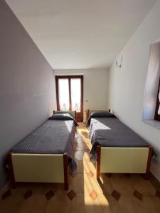 帕爾蓋利亞的住宿－Piccola Mansarda，带2扇窗户的客房内的2张床