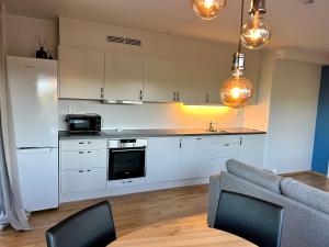 a kitchen with white cabinets and a table and a couch at Apartments in Kjeller Lillestrøm - New, Modern and Central in Lillestrøm
