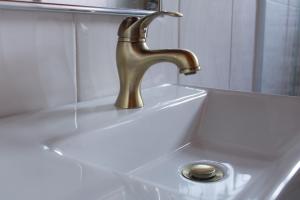 a bathroom sink with a brass faucet and a drain at Pousada Villa Paty - Campos do Jordão in Campos do Jordão