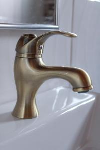 a bronze sink faucet on a white sink at Pousada Villa Paty - Campos do Jordão in Campos do Jordão