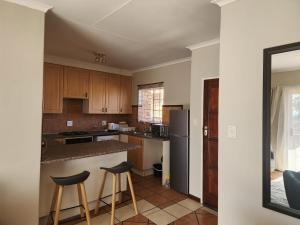 a kitchen with a counter and two stools in it at Mooikloof Village Apartment with Solar Backup in Pretoria