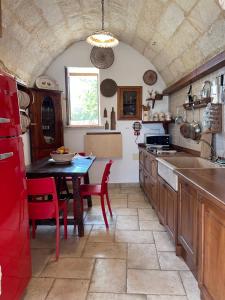 a kitchen with a table and red chairs in it at Oliventu - Tra gli ulivi sul mare in Gagliano del Capo
