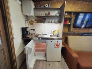 a small kitchen with a sink and a refrigerator at Skaisto saulrietu namiņš in Lembuži