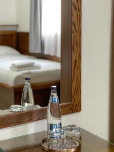 duas garrafas e copos numa mesa em frente a um espelho em Apartments & Rooms Brijest em Plav