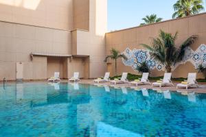 a swimming pool with lounge chairs in a building at Le Meridien Jeddah in Jeddah