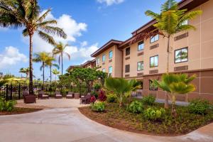 a building with palm trees and chairs in a courtyard at Courtyard by Marriott Oahu North Shore in Laie
