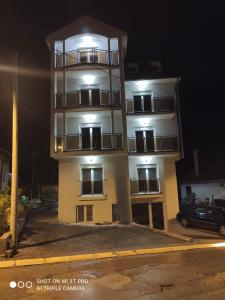 a tall white building with lights on it at night at Vila Pčelica Petra in Soko Banja