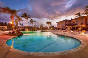 a pool at a resort with chairs and palm trees at Courtyard by Marriott Oahu North Shore in Laie