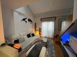 salon z białą kanapą i telewizorem z płaskim ekranem w obiekcie Maravilloso Ático-duplex w mieście Vigo