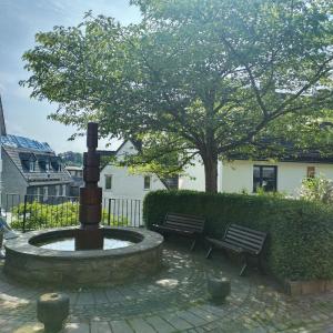 a fountain in a yard with two benches and a tree at Rubens Haus in Siegen