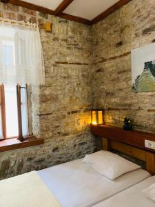 sypialnia z 2 łóżkami i kamienną ścianą w obiekcie Guest House and Hostel VAL-MAR w Gjirokastrze