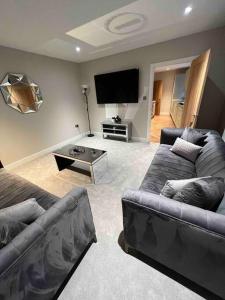 a living room with two couches and a flat screen tv at Cosy newly renovated 3 bedroom house - Town centre Horncastle in Lincolnshire
