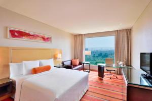 プネにあるコートヤード マリオット プネー ヒンジャワディのベッドと大きな窓が備わるホテルルームです。