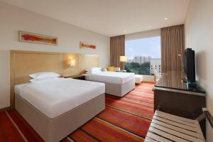 a hotel room with two beds and a flat screen tv at Courtyard by Marriott Pune Hinjewadi in Pune