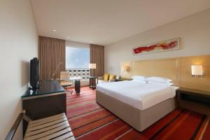 a hotel room with a bed and a flat screen tv at Courtyard by Marriott Pune Hinjewadi in Pune