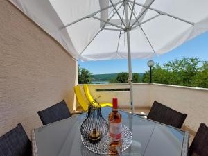 una mesa con dos botellas de vino y una sombrilla en Apartment Marino, en Čižići