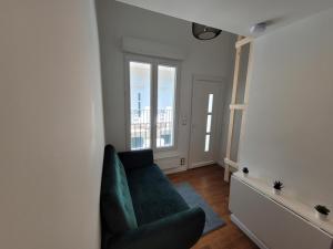 a living room with a green couch and a window at 2G- Studio tout équipé avec cuisine proche Paris in Issy-les-Moulineaux