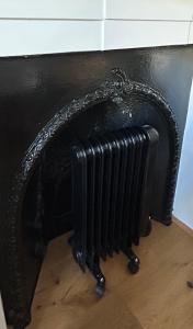 un radiador negro sobre una chimenea en 1 bedroom apartment in Shepherds Bush, London, en Londres