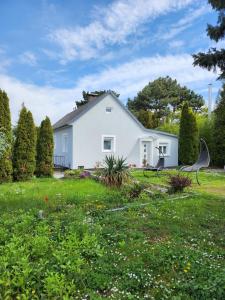 ein weißes Haus mit einem Rasenplatz mit einer Bank in der Unterkunft HOME 2201 in Gerasdorf bei Wien