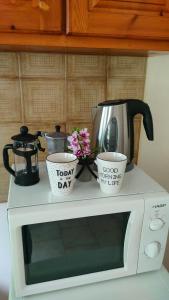 a microwave with two cups and a coffee pot and flowers at Vasiliki see view apartments in Barbati
