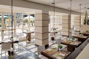 un restaurante con mesas, sillas y ventanas grandes en Sheraton Universal, en Los Ángeles