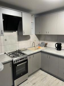 cocina con armarios blancos, fogones y fregadero en Апартаменти, en Beregovo