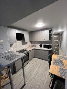 una pequeña cocina con armarios blancos, una mesa y un tocador en Апартаменти, en Beregovo