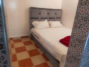 a small bedroom with a bed and a checkered floor at Appartement Relax Marrakech, شقة عائلية بمراكش متوفرة على غرفتين in Marrakesh