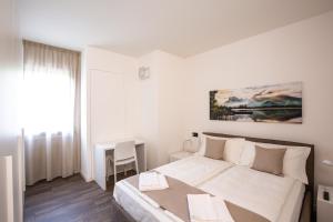 a white bedroom with a bed and a table at BORGO VERTICALE Luxury Apartments in Feltre