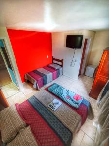 um quarto com duas camas e uma parede vermelha em Pousada do Gil em Teresópolis