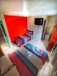 a room with two beds and a red wall at Pousada do Gil in Teresópolis