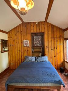 1 dormitorio con 1 cama azul en una habitación con paredes de madera en Private house surrounded by nature, en Forestburgh