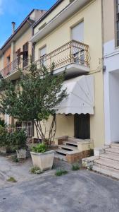 ein Gebäude mit einem Balkon, einem Baum und einer Treppe in der Unterkunft Casa centrale parcheggio gratis in Porto San Giorgio