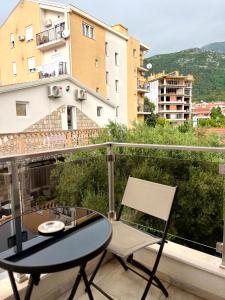 a glass table and a chair on a balcony at Pearl Apartments in Budva