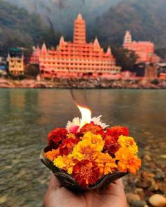 a person holding a bouquet of flowers in front of a building at Krishna Kunj Homestay Rishikesh in Rishīkesh