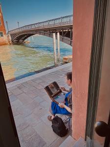 chłopiec siedzący w budynku z laptopem w obiekcie Al Ponte Lungo - Giudecca w Wenecji