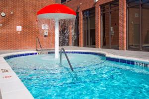 a swimming pool with a red umbrella in the water at SpringHill Suites by Marriott Wilmington Mayfaire in Wilmington