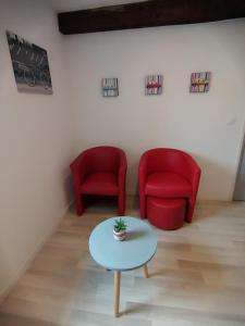 uma sala de estar com duas cadeiras vermelhas e uma mesa em Le Vélo Vintage, Beau 2 pièces centre ville em Tonneins