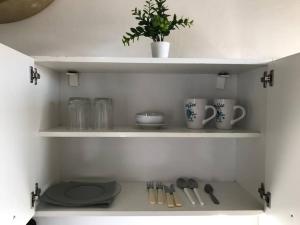 estante con tazas y utensilios en la cocina en Monoambiente Santa Rita, en Piriápolis