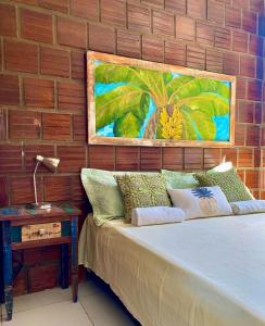 um quarto com uma cama com um quadro na parede em Chalé Capixaba em Gravatá