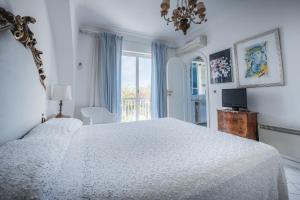 a white bedroom with a large bed and a window at Villa Domenicanda in Capri