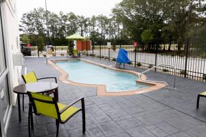 uma piscina com uma mesa e cadeiras e uma mesa e cadeiras em SpringHill Suites by Marriott Slidell em Slidell