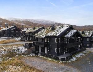 eine Gruppe von Häusern mit Schnee auf den Dächern in der Unterkunft Bo lunt og koselig på Filefjell in Tyinkrysset