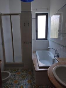 uma casa de banho com uma banheira, um lavatório e uma janela em Vivere il mare em Palinuro