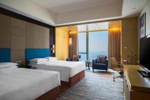 a hotel room with two beds and a flat screen tv at Renaissance Huizhou Hotel in Huizhou